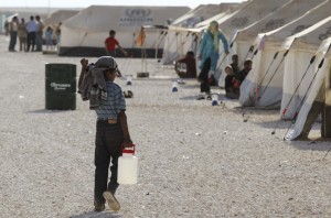 A Syrian refugee boy carries water for his family at the Zaatari refugee camp in Mafraq